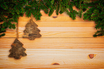 Christmas or New Year decoration background with hanging brown trees in pine branches on a wooden table with copy space.