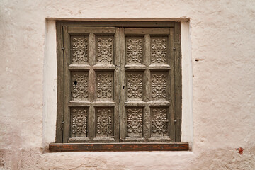 Antique looking wooden window shutters with wood carvings and ornaments in mediterranean style as in Italy or Spain