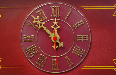 Burgundy watch dial with gold hands, close-up.