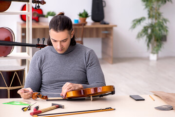 Young male repairman repairing violin