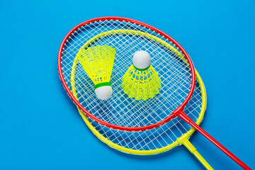 Two shuttlecock and badminton rackets on blue background. Active recreation and sports concept.