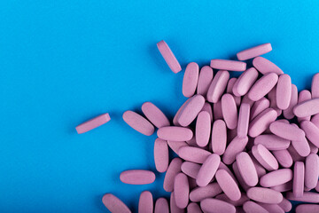 Pink pills on a blue background. Health care concept. Space for text. Conservative medicine.