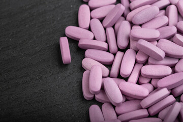Obraz na płótnie Canvas Pink pills on a black background. Health care concept. Space for text. Conservative medicine.