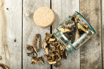 Dried mushrooms in a glass jar on a wooden table. Space for text.