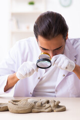 Young male archaeologist studying ancient african stonemask