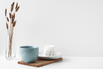 Blue mug and meringue cake on a white background. Eco-friendly and natural materials in decor and interior design, dessert. Copy space, mock up.