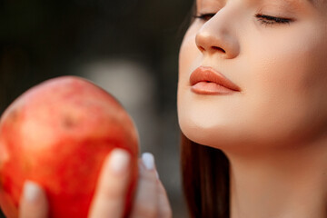 close-up portrait of a young beautiful girl with a pomegranate in her hands. shallow DOF. selective focus.