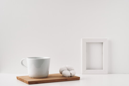 Frame, cotton and a cup on a wooden board, white background. Mock up, copy space. Folk. © Natalya Lys