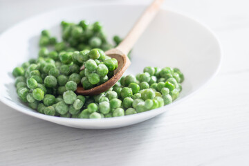 green peas in a white plate on a white background