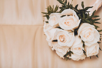 flowers ,  wedding bouquet of white roses with 2 gold wedding rings on a beige