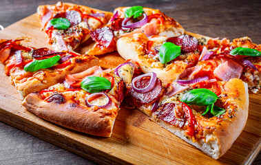 Pizza with Mozzarella cheese, ham, tomato sauce, salami, onion, pepper, Spices and Fresh basil. Italian pizza on wooden table background