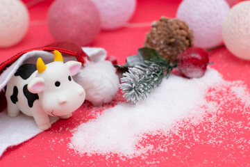 Decorations for the new year, postcard design. Toy bull in a santa hat, new year garland, snow. A photo