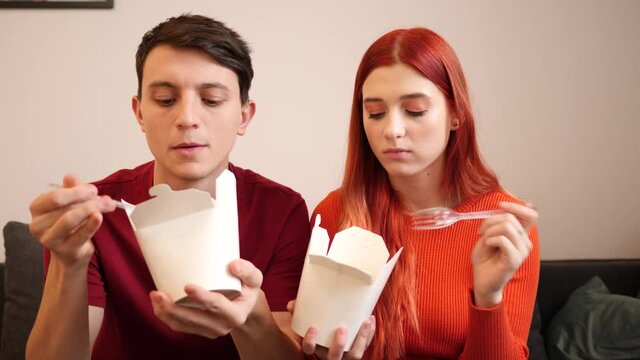 Young couple stay at home eat dober kebab takeaway boxes from food delivery watching tv
