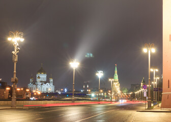 Moscow, Russia. The Kremlin - wall, towers.  Kremlevskaya embankment in night. Cathedral of Christ the Saviour in background