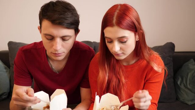 Young couple stay at home eat dober kebab takeaway boxes from food delivery watching tv