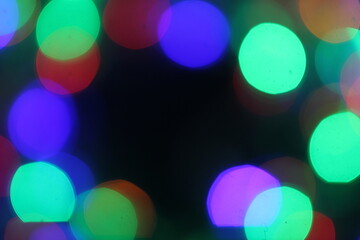 Bright, multicolored bokeh lights of Christmas garland on a black background, texture of new years lights for design.