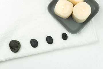 Obraz na płótnie Canvas Gray zen pebble hot stones with towel on massage table in beauty salon. Hot stone massage setting. Concept set of harmony, balance and meditation, spa, relax, spa treatment