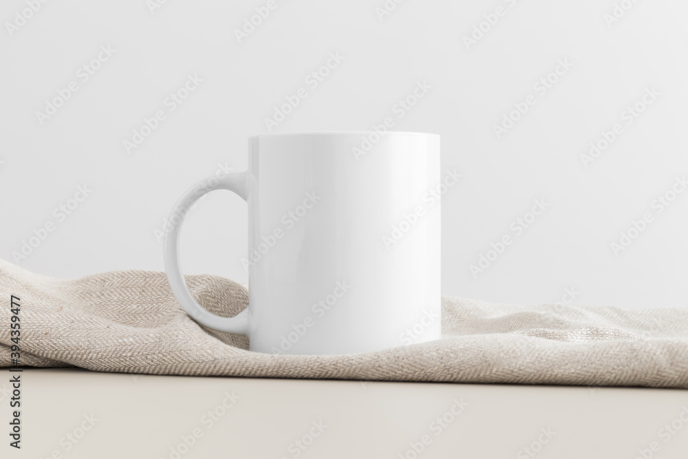 Sticker White mug mockup with a table cloth on a beige table.