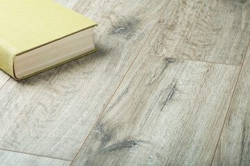 Laminate background. Book on the floor. Wooden laminate and parquet boards for the floor in interior design. .