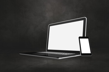 Laptop and mobile phone on dark concrete office scene