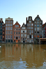 Naklejka premium Traditional dutch houses lining Damrak canal in Amsterdam, Netherlands. Vertical photo.