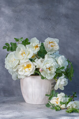 White garden roses in a bouquet on a gray background. Still life with white rosehip flowers in a vase. Selective focus