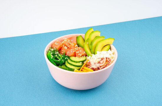 An overhead diagonal, isometric projection photo of poke bowl, traditional Hawaiian and Japanise raw fish salad, from seaweed, rice, salmon, cucumber, soy sause and avocado. with chopsticks and sesame