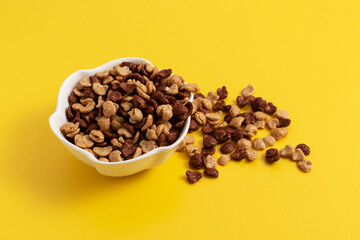 Mix of light and dark dry flakes in a plate on a yellow background.