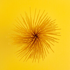 Uncooked dried spaghetti pasta on yellow background. Top view.