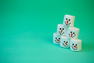 marshmallow snowman on mint turquoise background with garland lighting