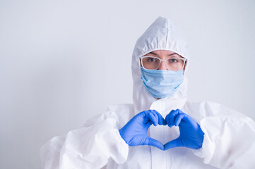 Female doctor in a protective suit shows the heart with a gesture. Patient health care concept