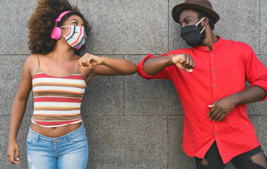 African friends wearing face protective mask while doing new social distance greetings bumping elbows - Youth millennial people and health care guidelines to avoid corona virus spread © Alessandro Biascioli