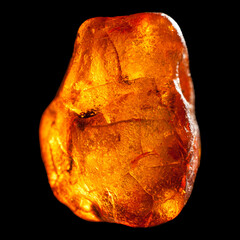 Macro close-up of rough raw amber stone isolated on black background.