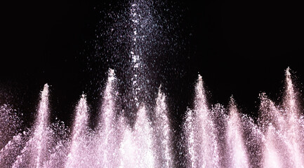 Water fountain on a dark background. Jet and spray in motion.