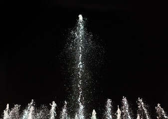 Water fountain on a dark background. Jet and spray in motion. - obrazy, fototapety, plakaty