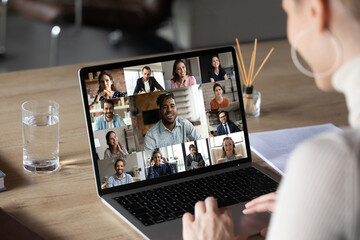 Smiling female employee using computer software application, holding video conference online call...