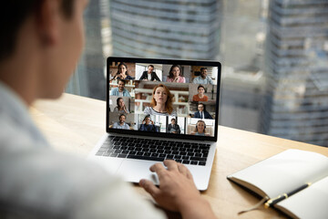 Shoulder back view female businesswoman looking at laptop screen, briefing discussing working issues with diverse multiracial colleagues by video call app, happy people communicating online distantly.