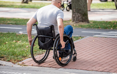Fototapeta premium Handicapped man in wheelchair crossing street road