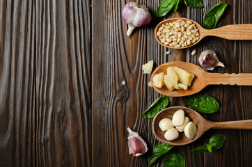 Flat lay view at wooden spoons with food ingredients for genovese pesto sauce on kitchen table