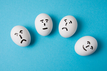 Eggs with faces and different emotions: indifference, sadness, anger and joy. Isolate on a blue background.