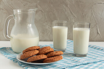a carafe of cool milk with oatmeal cookies - the taste of childhood. concrete background, blue...