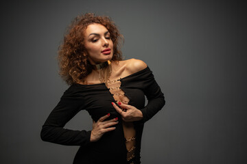 curly girl in black clothes on a gray background in a photo studio