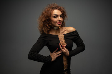 curly girl in black clothes on a gray background in a photo studio