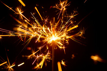 Sparks from Christmas sparklers on black background, big bang, fire and danger, selective focus,...