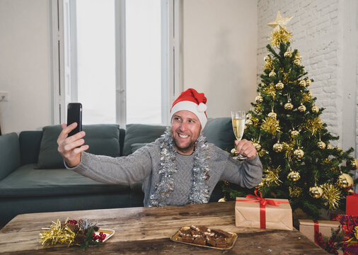 Happy man with mobile phone on video call celebrating christmas with family at home in lockdown
