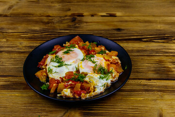 Homemade breakfast shakshuka - fried eggs, onion, bell pepper, tomatoes and dill on rustic wooden table. Jewish cuisine