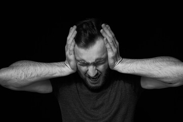 A man on a black background covers his ears with his hands. Reluctance to hear.I don't hear evil.