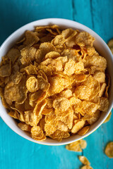 Bowl with tasty corn flakes on wooden table. Top view.