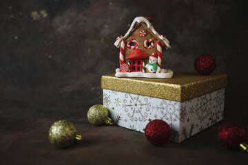 Christmas or New Year background.  Gingerbread house toy on gift box on dark background