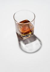 Glass of whiskey on white background with had reflections